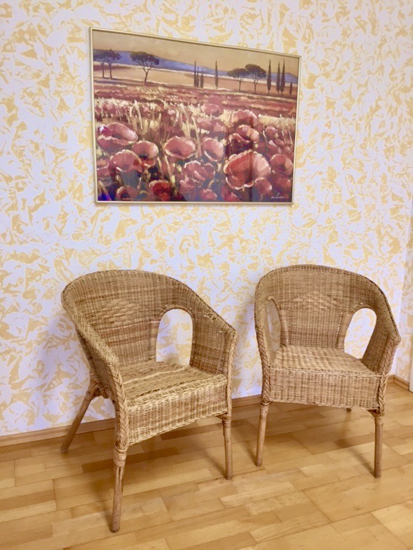 Sitzecke mit Kunstdruck und Grünpflanze im Wartebereich